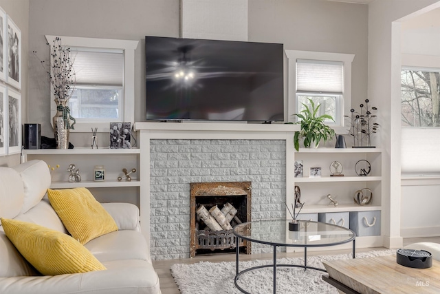 living area featuring wood finished floors, built in features, and a fireplace