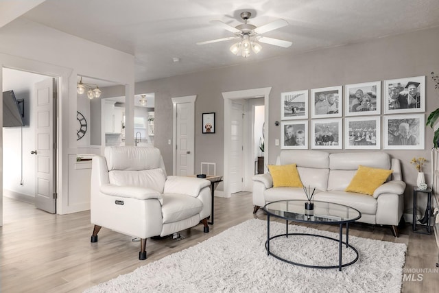 living area featuring light wood-style flooring and ceiling fan