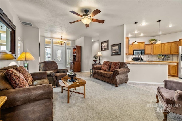 living room with ceiling fan with notable chandelier, light colored carpet, and sink