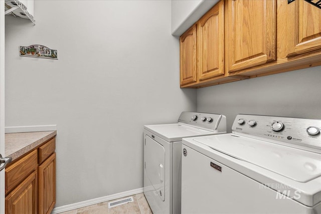 laundry room featuring independent washer and dryer and cabinets