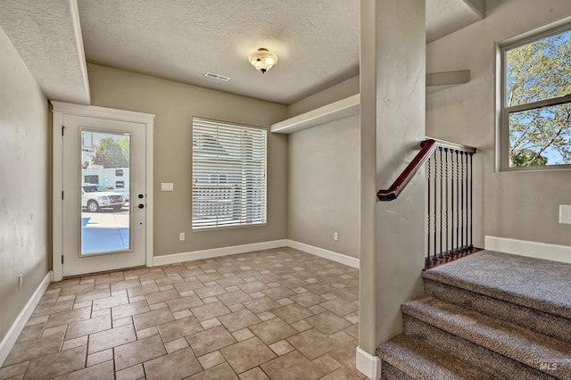 5278 N Cougar Flat Pl, Meridian, ID 83646 - entrance foyer featuring stone finish flooring, a textured ceiling, visible vents, baseboards, and stairway