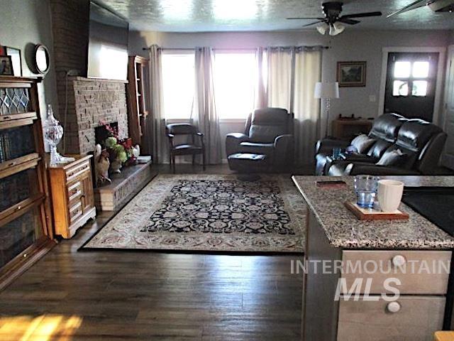 living room with a textured ceiling, dark hardwood / wood-style floors, and ceiling fan