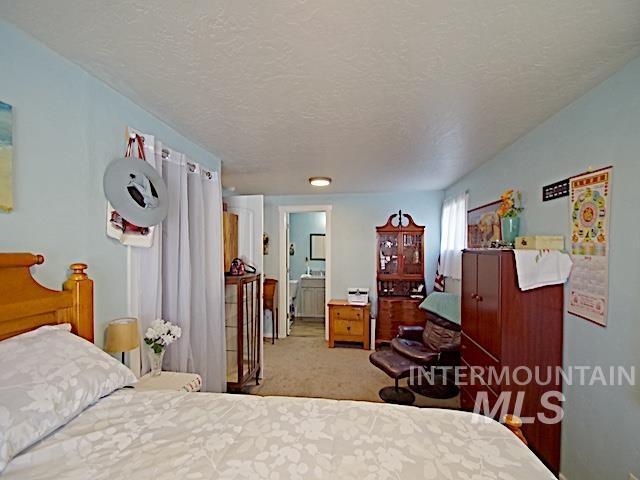 carpeted bedroom featuring connected bathroom and a textured ceiling