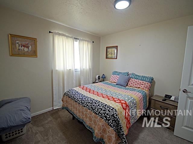 bedroom with dark colored carpet and a textured ceiling