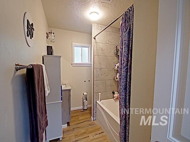 bathroom with vanity, hardwood / wood-style floors, shower / bath combination with curtain, and a textured ceiling