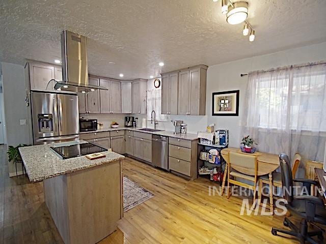 kitchen with sink, island range hood, a textured ceiling, light hardwood / wood-style floors, and black appliances