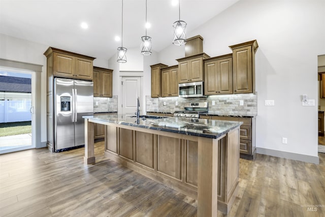 1487 Zephlyn St, Twin Falls, ID 83301 - kitchen featuring dark stone counters, stainless steel appliances, sink, hanging light fixtures, and an island with sink
