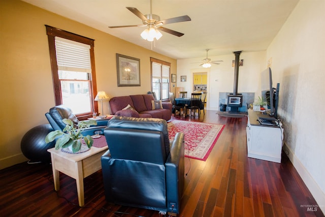 599 S Ada St, Glenns Ferry, ID 83623 - living area featuring a wood stove, a ceiling fan, dark wood-type flooring, and baseboards