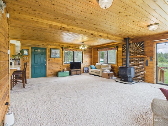 19 Hack Ln, Idaho City, ID 83631 - carpeted living area featuring wood walls, a wood stove, healthy amount of natural light, a ceiling fan, and wooden ceiling