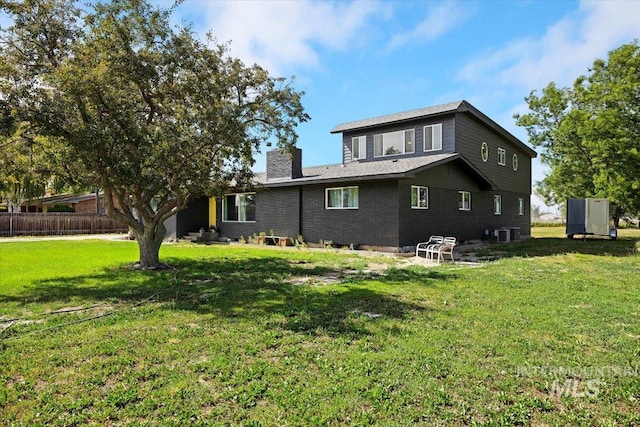 rear view of property featuring a lawn and central air condition unit