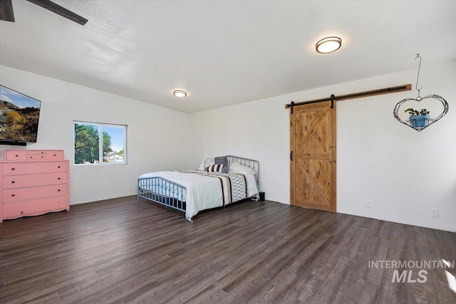 unfurnished bedroom with dark wood-type flooring and a barn door