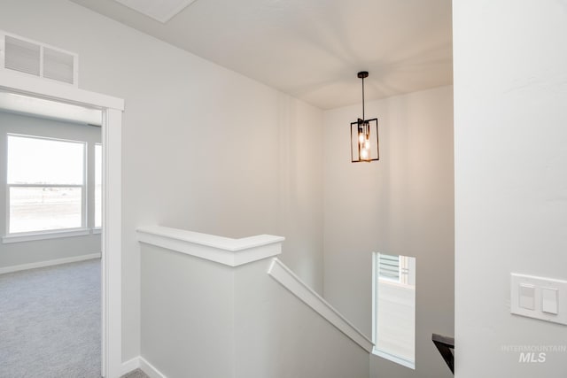 hall featuring carpet and a notable chandelier