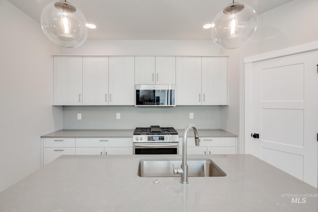 kitchen with decorative backsplash, appliances with stainless steel finishes, white cabinetry, and sink