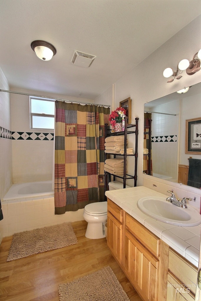 full bathroom with vanity, toilet, hardwood / wood-style floors, and shower / bath combo with shower curtain