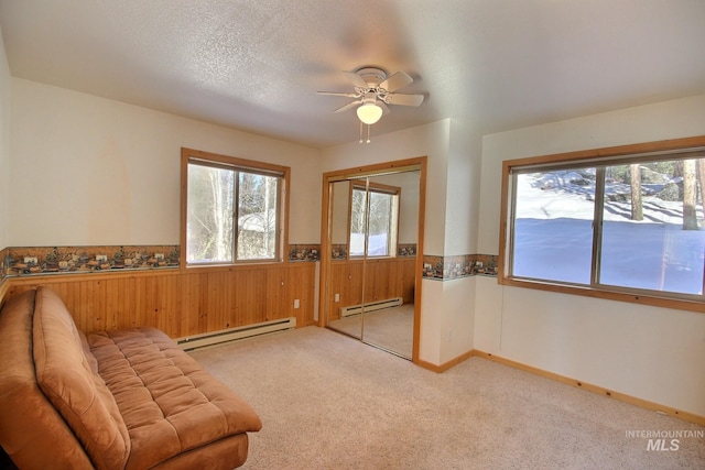 living area with ceiling fan, a baseboard radiator, light carpet, and a textured ceiling