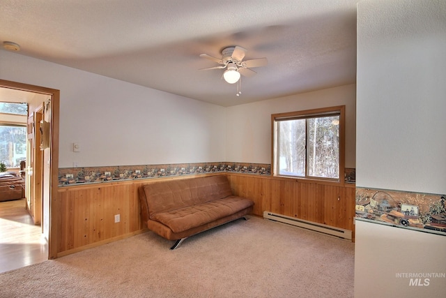 living area featuring a baseboard radiator, light carpet, and wood walls