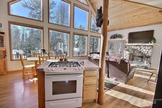 kitchen featuring white gas range, a healthy amount of sunlight, tile countertops, and light hardwood / wood-style flooring