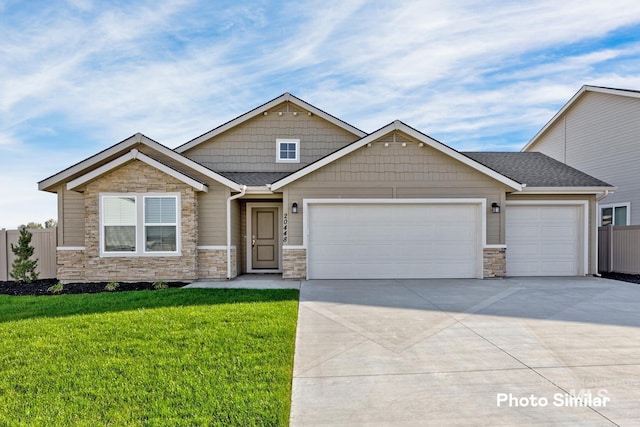 craftsman-style house with a garage, concrete driveway, stone siding, fence, and a front yard