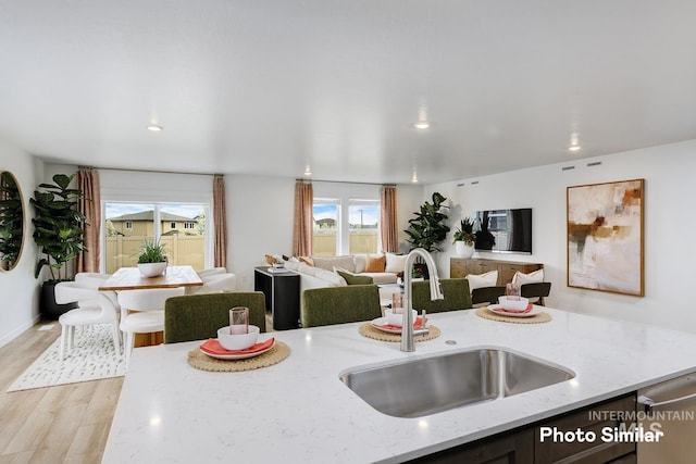 kitchen featuring open floor plan, light stone counters, a sink, and a wealth of natural light