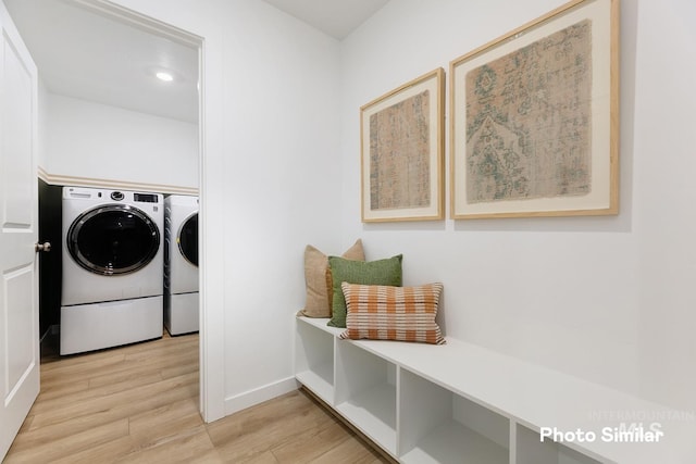 laundry area featuring baseboards, washing machine and clothes dryer, laundry area, and light wood-type flooring