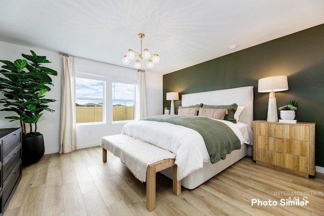 bedroom featuring light wood finished floors, baseboards, and a notable chandelier