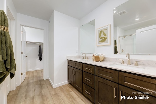 bathroom with a spacious closet, visible vents, a sink, and wood finished floors