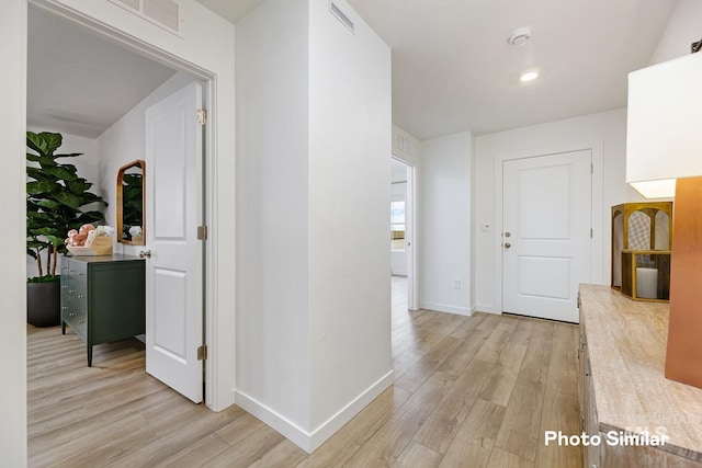 hall with light wood finished floors, baseboards, and visible vents