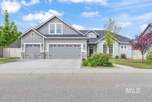 view of front of home featuring driveway, board and batten siding, a garage, and stone siding