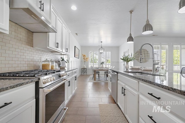 kitchen with stainless steel appliances, under cabinet range hood, a sink, backsplash, and white cabinetry