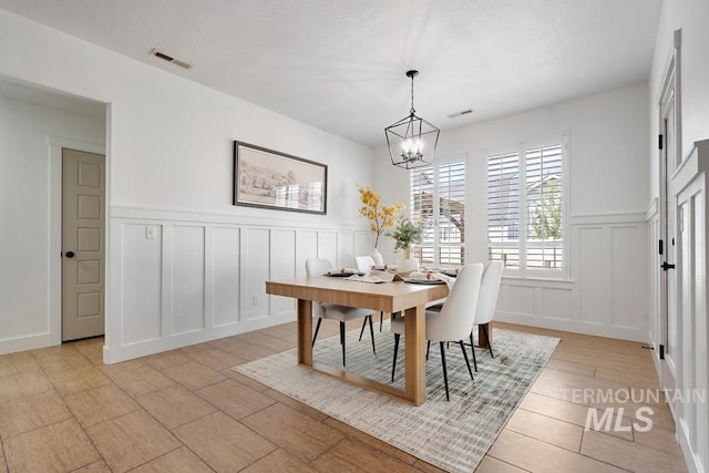 dining room with a decorative wall, a chandelier, and a wainscoted wall