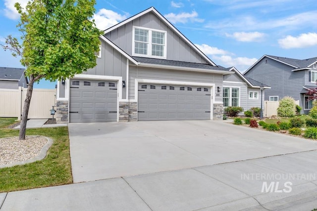 craftsman-style house featuring board and batten siding, concrete driveway, fence, stone siding, and a garage