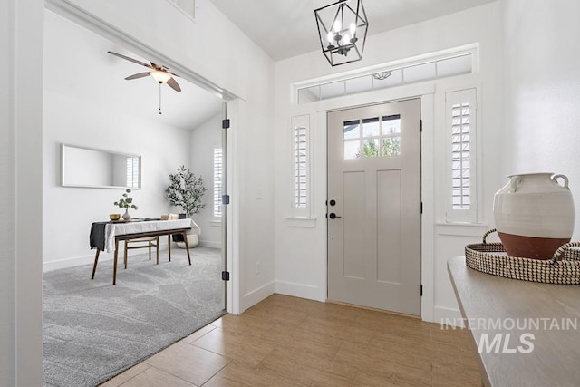 entrance foyer featuring a chandelier, ceiling fan, and baseboards