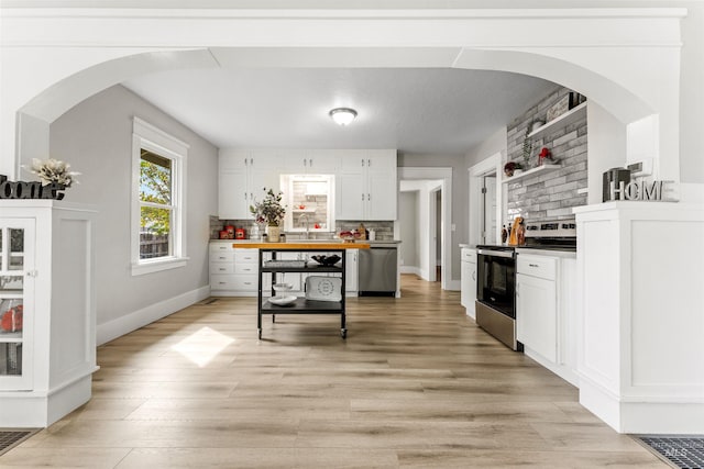 kitchen with sink, tasteful backsplash, white cabinetry, appliances with stainless steel finishes, and light wood-type flooring