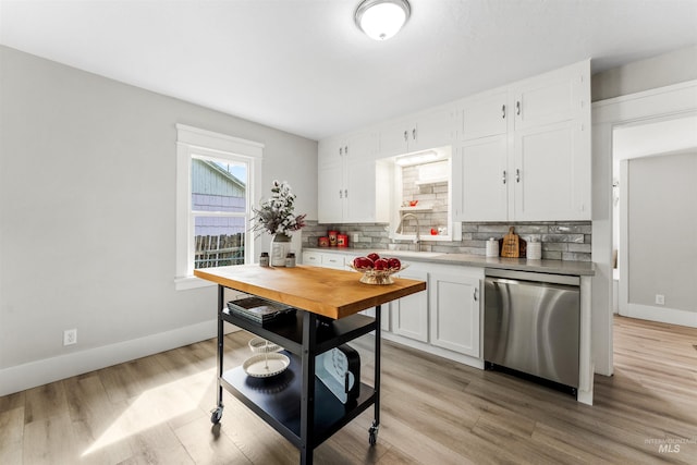 kitchen with tasteful backsplash, light hardwood / wood-style flooring, sink, stainless steel dishwasher, and white cabinetry