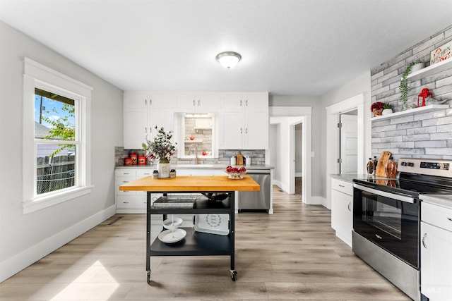 kitchen featuring appliances with stainless steel finishes, light wood-type flooring, white cabinetry, and backsplash