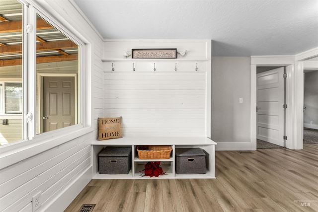 mudroom featuring hardwood / wood-style flooring and wooden walls