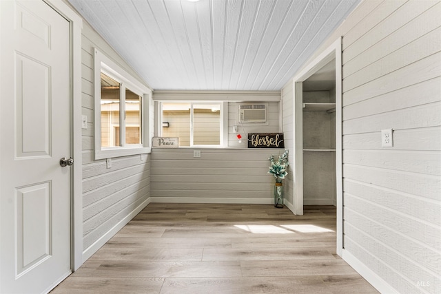 interior space featuring a wall mounted AC, wooden walls, and light wood-type flooring