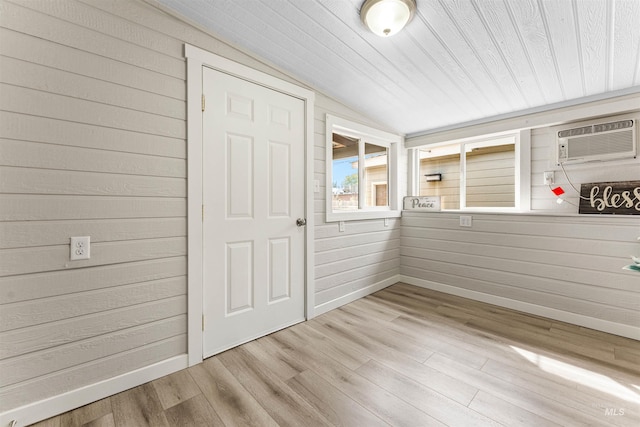 interior space with wood ceiling, lofted ceiling, wooden walls, light wood-type flooring, and a wall mounted air conditioner