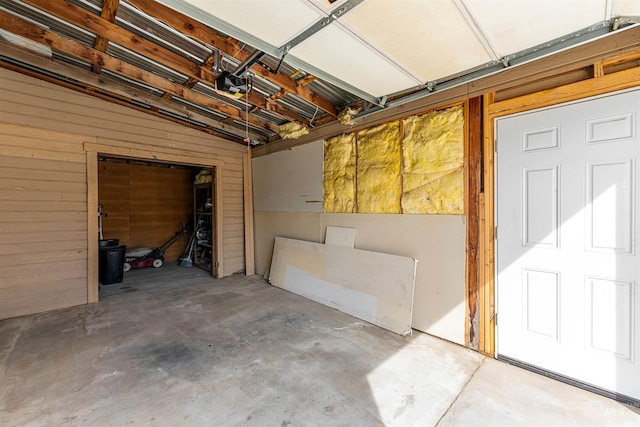 garage featuring a garage door opener and wooden walls