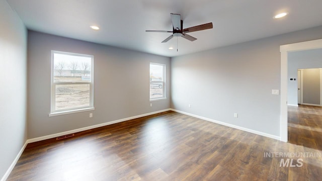 empty room featuring ceiling fan, dark hardwood / wood-style floors, and a wealth of natural light