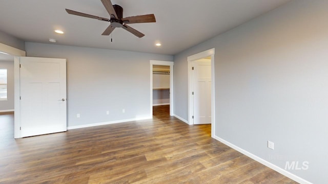 interior space featuring dark hardwood / wood-style flooring, a spacious closet, a closet, and ceiling fan