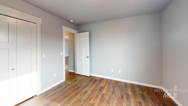 unfurnished bedroom with dark hardwood / wood-style flooring and a closet