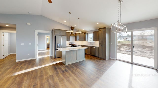 kitchen with hanging light fixtures, stainless steel appliances, sink, and a kitchen island