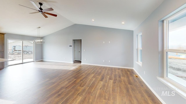 unfurnished living room featuring ceiling fan with notable chandelier, plenty of natural light, dark hardwood / wood-style flooring, and vaulted ceiling