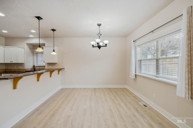 unfurnished dining area featuring recessed lighting, visible vents, light wood-style floors, a textured ceiling, and baseboards