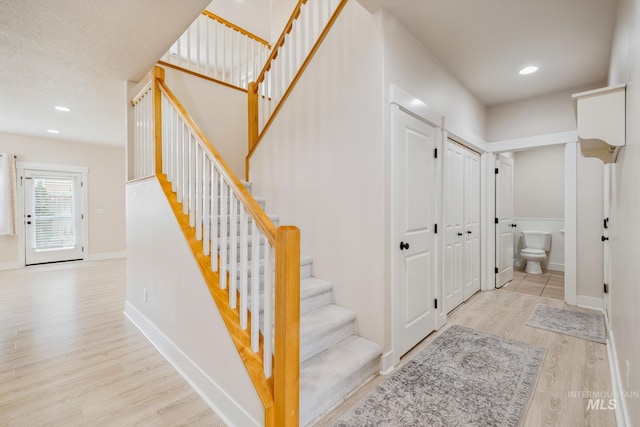 staircase with recessed lighting, wood finished floors, and baseboards