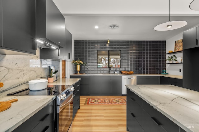 kitchen featuring stainless steel appliances, wall chimney range hood, pendant lighting, and light stone counters