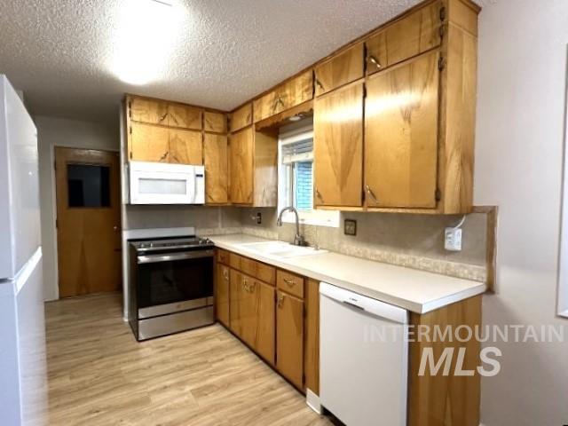 995 E 15th N, Mountain Home, ID 83647 - kitchen with a sink, white appliances, light countertops, a textured ceiling, and light wood-style flooring