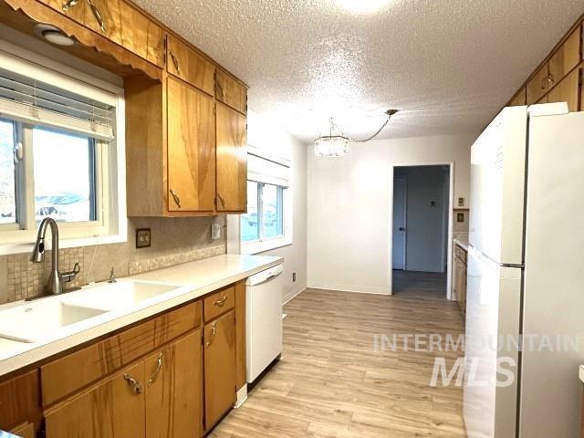 995 E 15th N, Mountain Home, ID 83647 - kitchen featuring white appliances, light wood-style floors, light countertops, a textured ceiling, and a sink