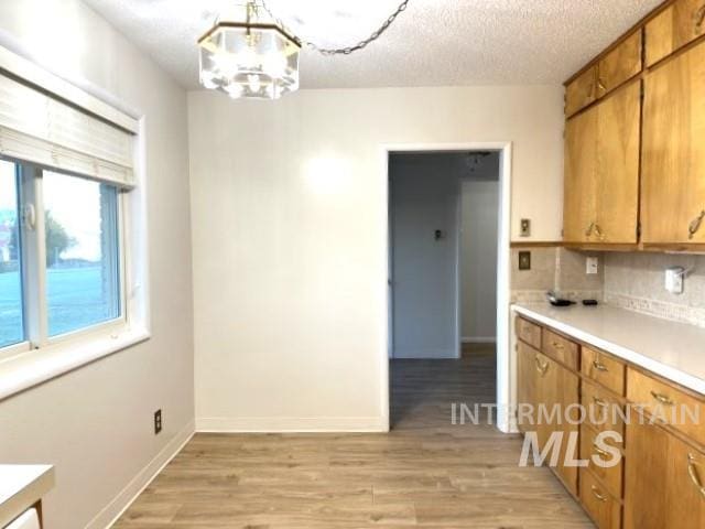 995 E 15th N, Mountain Home, ID 83647 - kitchen with tasteful backsplash, brown cabinets, light countertops, a notable chandelier, and light wood-style flooring
